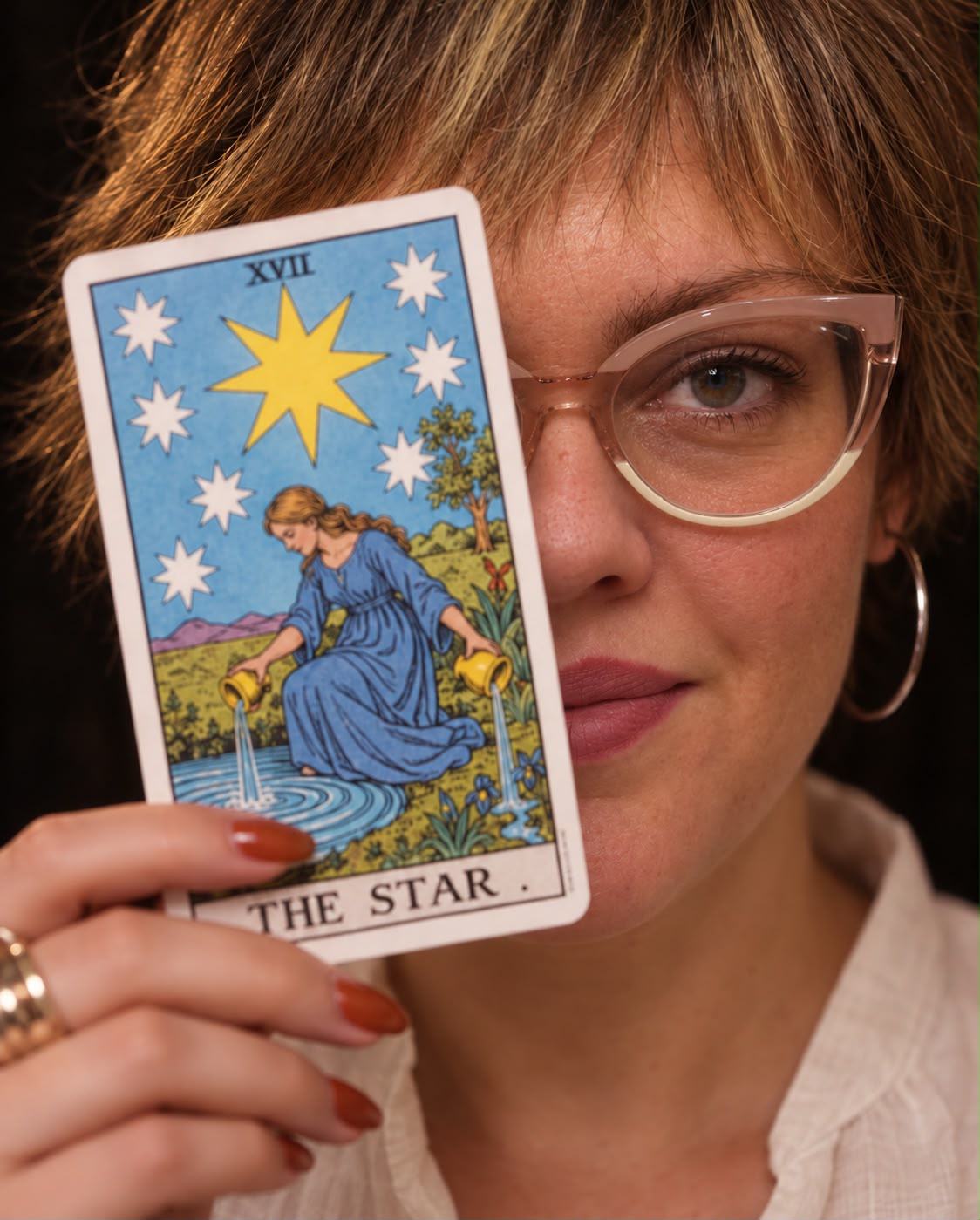 Fernanda Gonçalves segurando a carta A Estrela diante do rosto